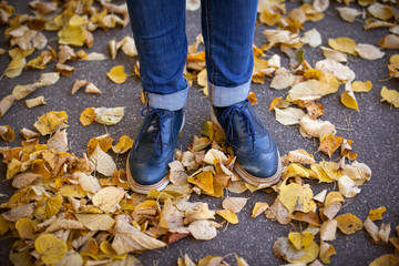 foots on the ground with autumn leafs, blue shoes.