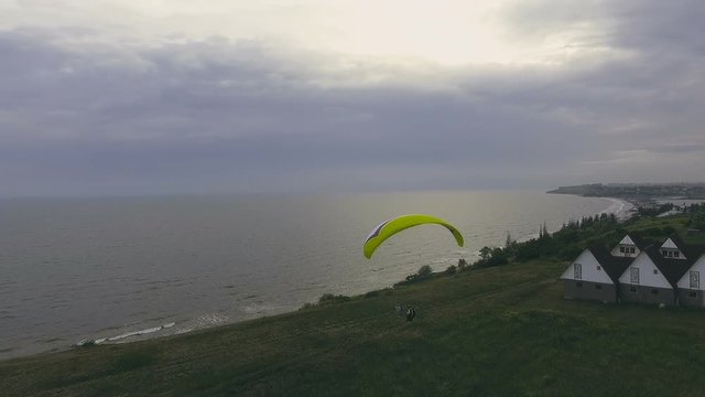 Paraplane, paraglider in the air aerial shot. Extreme man flies on a paraglider over a cliff near the sea. Extreme life.