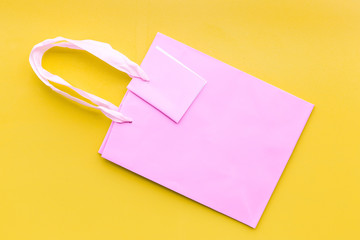 Pink shopping bag on yellow background top view mockup