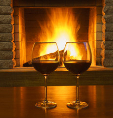 Two Glasses  of  red wine   near  cozy fireplace, in country house, winter vacation.