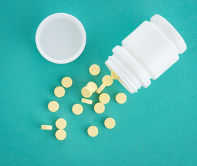 Yellow pills with bottle on green mint background, Healthy and Medicine concept