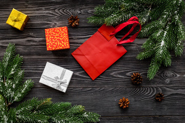 Christmas gifts. Wrapped boxes near spruce branches on dark wooden background top view