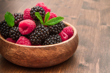 Wooden cup with fresh berries on wooden table