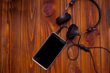 Smart phone and headphones on a wooden table