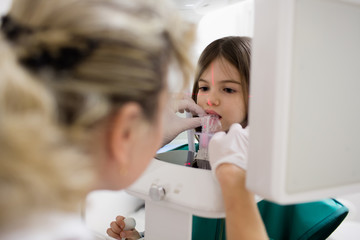 doctor makes a panoramic x-ray of teeth to a girl in a dental office
