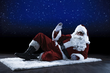Santa Claus on the carpet and the floor. Background of a night sky with a million stars. Place for your product and advertising text.