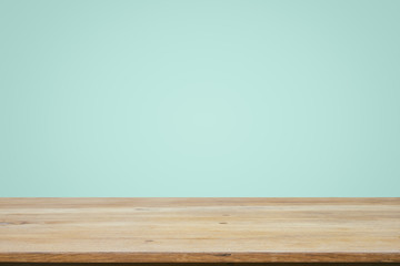 Empty wooden deck table over mint wallpaper background.