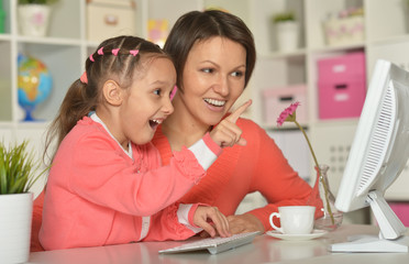 little girl  with mother using computer