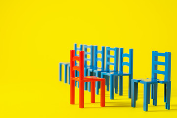 Unique red chair in a group blue others. Leadership concept. Empty chairs  on yellow background. The concept of uniqueness, distinction from others.