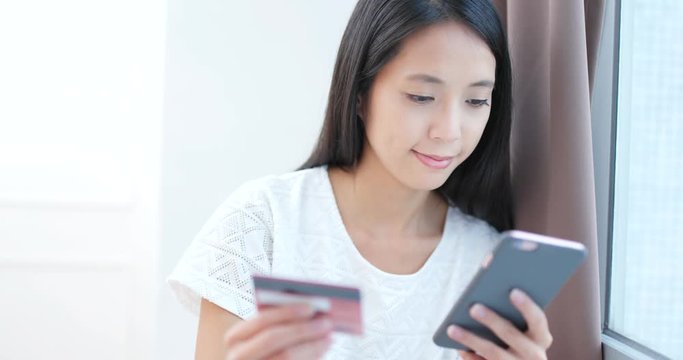 Woman using credit card to pay the bill on cellphone