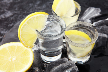 Tequila shot with lime and sea salt on table.