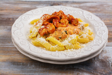 Cooked italian pasta arrabiata with chicken and tomato sauce on wooden table. Copy space