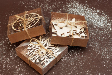 Eco Style Gift Wrapping. Three Gift Boxes Decorated with Wooden Laser Cut Snowflakes. Top view. Brown Background.