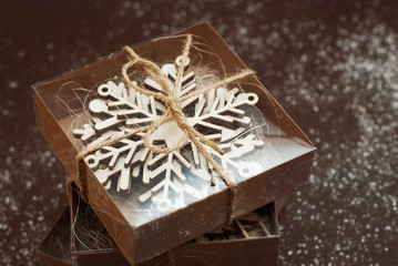 Top view of Gift Christmas Boxes. Presents in craft paper with laser cut snowflakes gift. Christmas, holidays concept. Brown background.