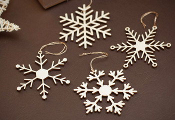 Laser Cut Wood Snowflakes Ornaments. Wooden Snowflakes on Brown Background. Christmas Holliday Concept.