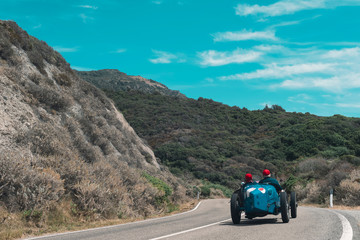 Classic sports car driving on mountain road in summer. Sardinia. Italy.
