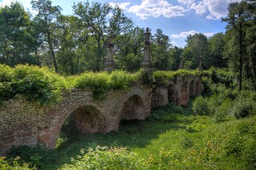 Ancient ruined overgrown red brick bridge in the forest