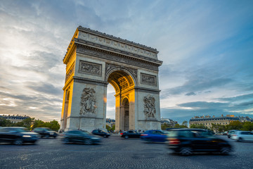 Fototapeta na wymiar Famous Paris avenue Champs-Elysees and the Triumphal Arch, symbol of the glory on bright sunny day with cloudy sky. Iconic touristic landmark and romantic travel destinations in France. Long exposure