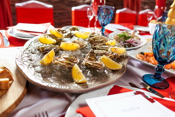 Oysters with lemon and ice on the plate on the dinner table