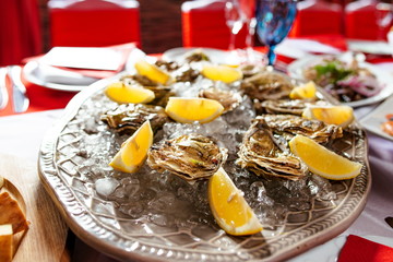 Oysters with lemon and ice on the plate on the dinner table