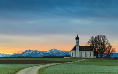 Sunrise over old chapel in green field