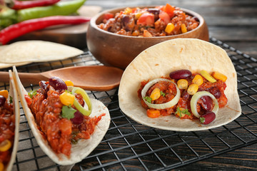 Delicious tacos with chili con carne on metal grid