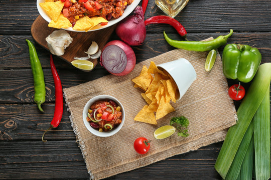 Bowl with chili con carne and nachos on table