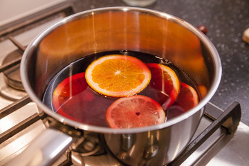 Cooking mulled wine, a pot on a plate with fruit.