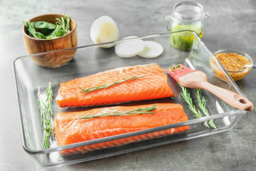 Baking dish with fresh raw salmon fillet ready for marinating on table