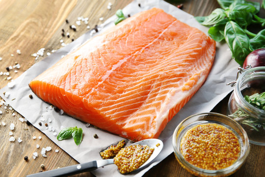 Fresh raw salmon fillet with honey mustard marinade on wooden table