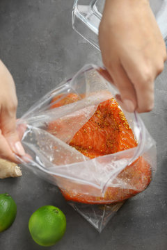 Woman Preparing Salmon Fillet With Honey Mustard Marinade In Zip Lock Bag On Table