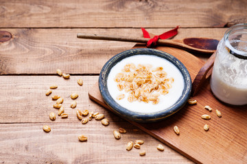 Dish of cereal with milk, glass of milk and wooden spoon 