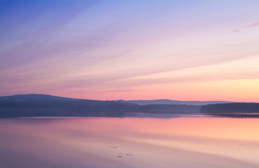 Fototapeta na wymiar Colourful summer sunset reflecting in calm a lake