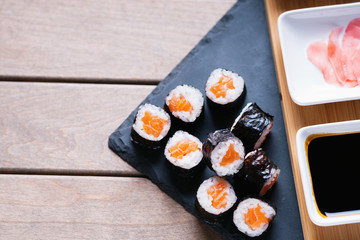 Sushi rolls with salmon and dishes with soy sauce and ginger