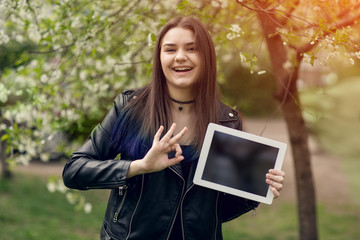 Portrait of young girl holding digital tablet in the park