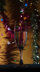 A champagne glass stands on the table. The photo on the background of Christmas light.