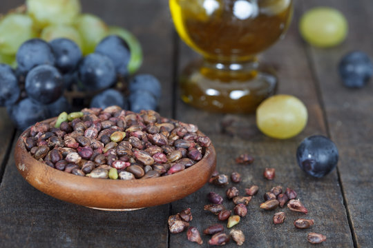 Grape seed in wooden bowl. Antioxidant, healthy grape seed oil and fresh grape on the table. Closeup view.