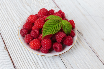Raspberries in a bowl on a wooden white table
