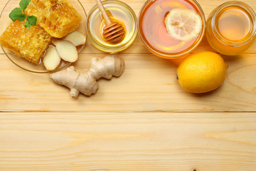 Fototapeta na wymiar healthy background. honey, honeycomb, lemon, tea, ginger on light wooden table. Top view with copy space