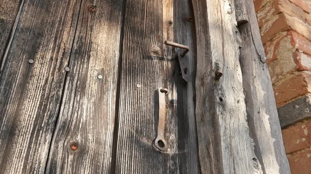 Slow tilt on rotten wooden planks and rusty lock footage - Old doors of abandoned house