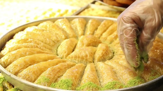 man puts peanuts on top of baklava slices