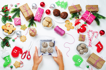 Christmas background with gifts, cookies, Christmas decoration and woman's hands holding cookies