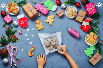 Fototapeta na wymiar Christmas background with gifts, cookies, Christmas decoration and children's hands holding cookies
