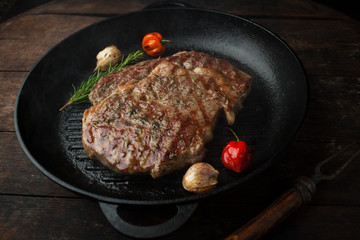 Grilled steak ribeye with salt, seasonings, and rosemary in a frying pan