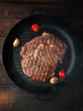 Grilled steak ribeye with salt, seasonings, and rosemary in a frying pan