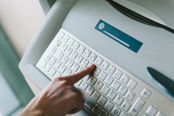 Modern filter over woman finger pressing the Y letter button on the metallic keyboard of ATM...