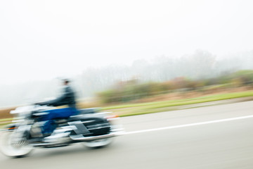 Fototapeta na wymiar Blur motion of cool hipster biker motorcyclist on German autobahn highway