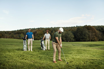 Golf player walking and carrying bag on course during summer game golfing