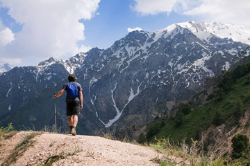 Young tourist in mountains with a walking pole