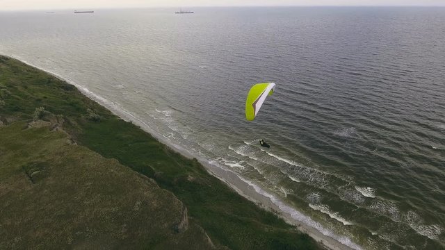Paraplane, paraglider in the air aerial shot. Extreme man flies on a paraglider over a cliff near the sea. Extreme life.